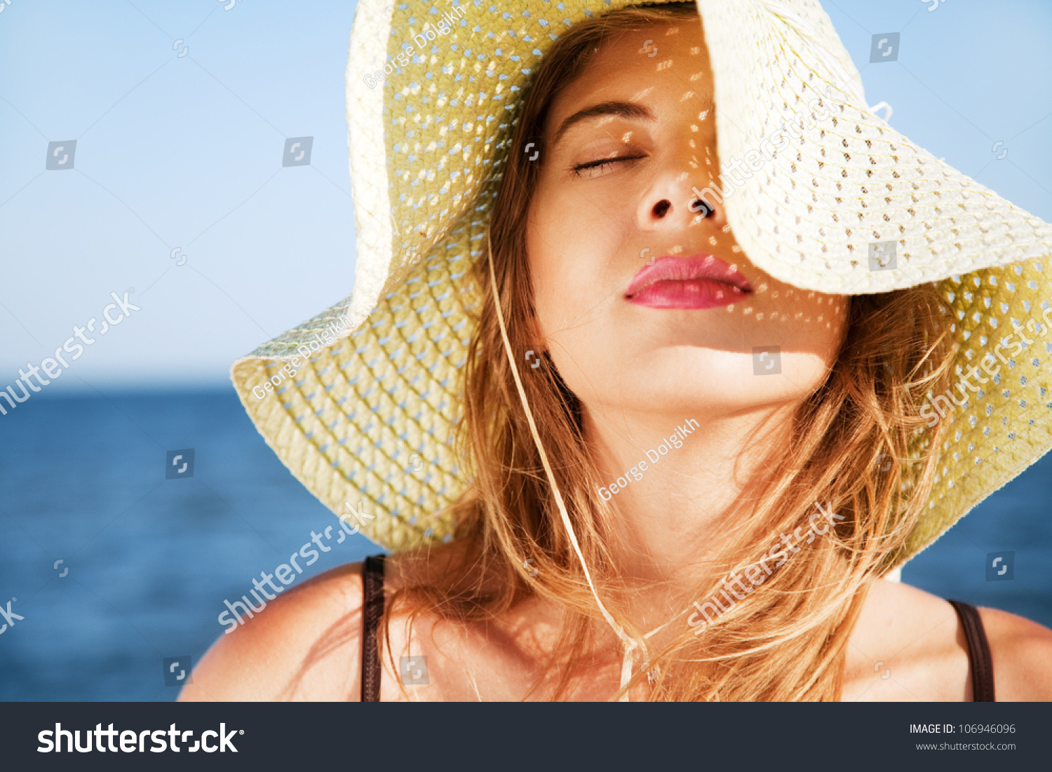 Young woman wearing a wide-brim straw sun hat on a sunny beach